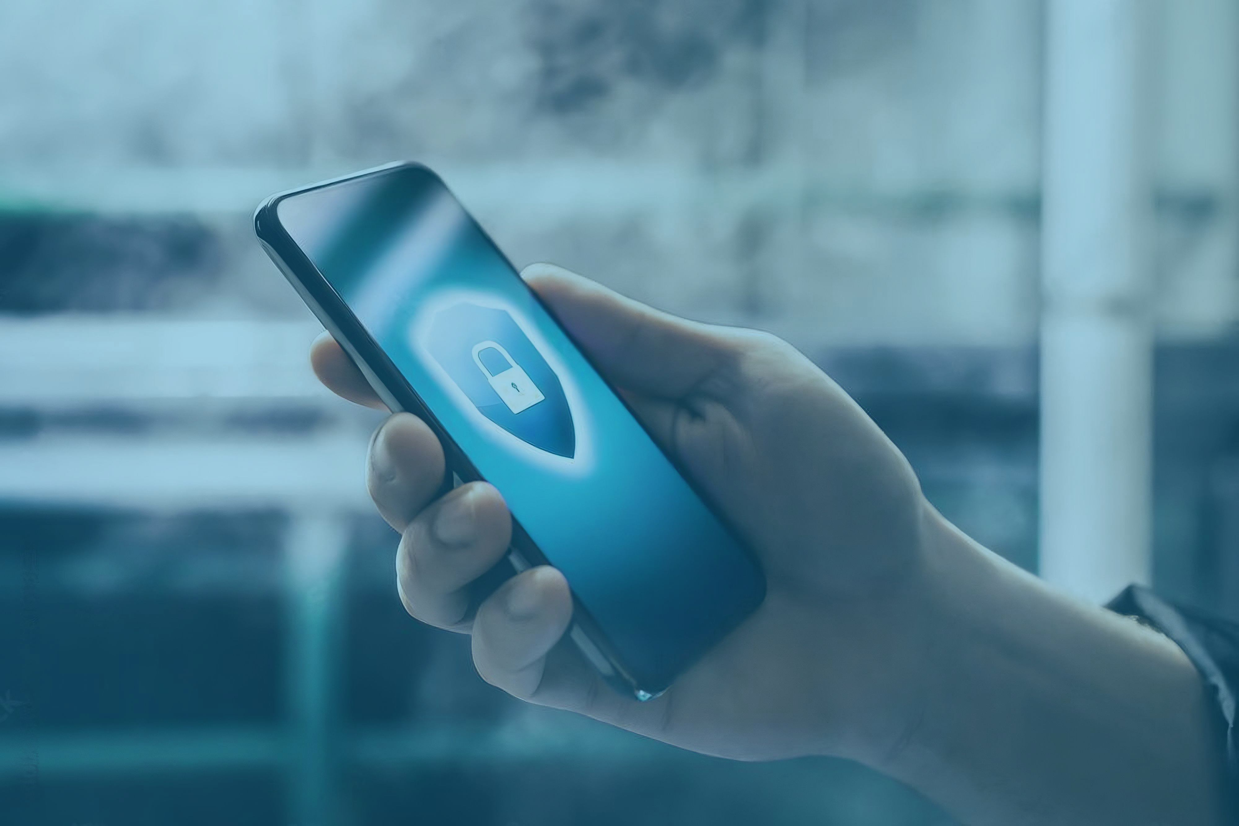 Mão esquerda segurando um celular enquanto a mão direita toca na tela com um fundo azul e um cadeado branco ao meio.